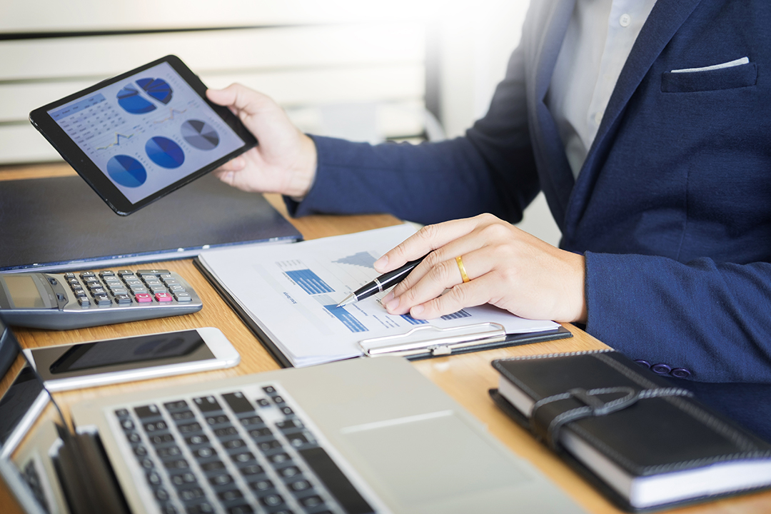 摄图网_378359230_商人在办公桌前进行财务分析工作(企业商用).jpg